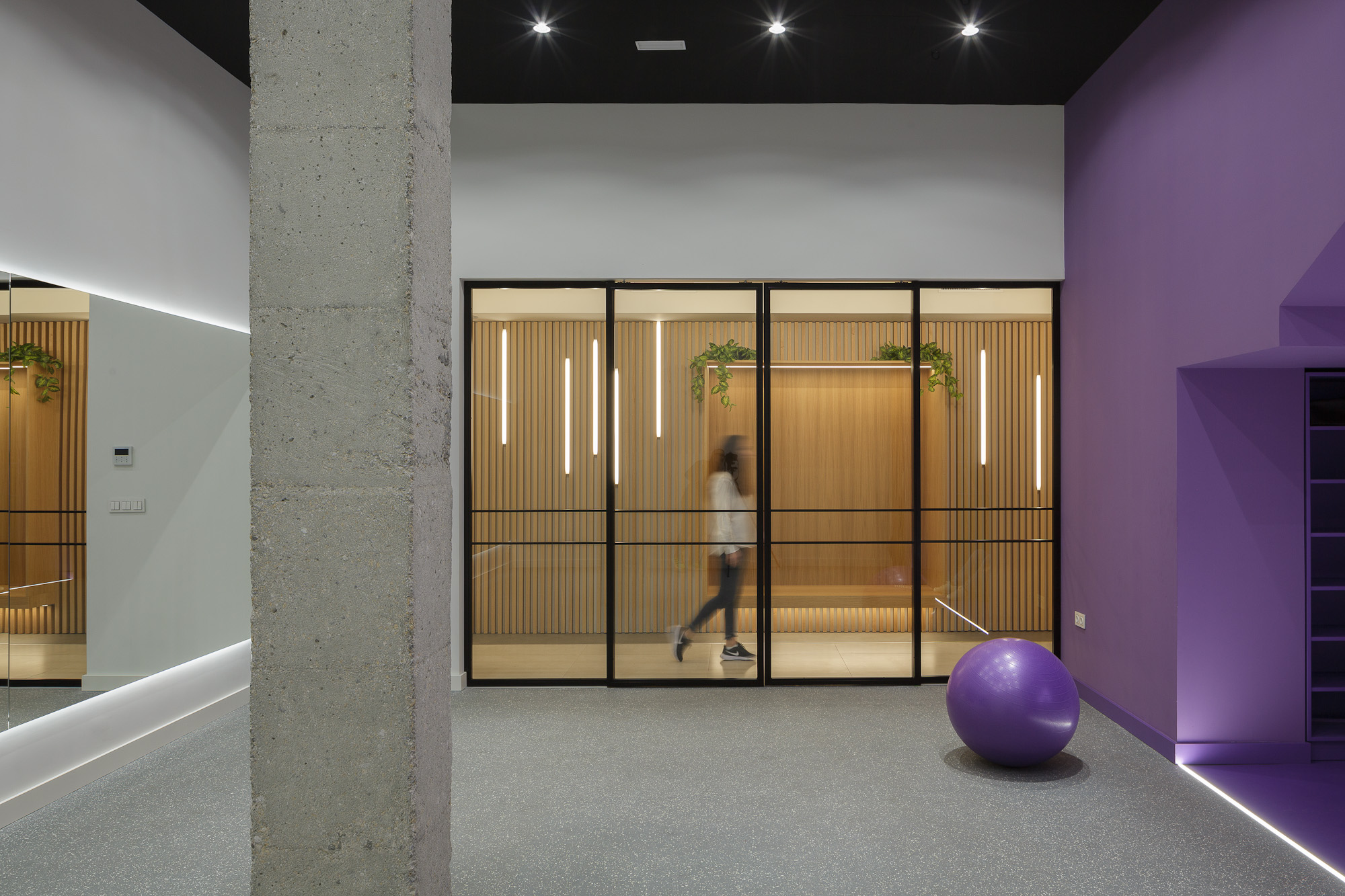 Visión interior de la sala de pilates con las puertas de hierro cerradas y una persona andando por el pasillo