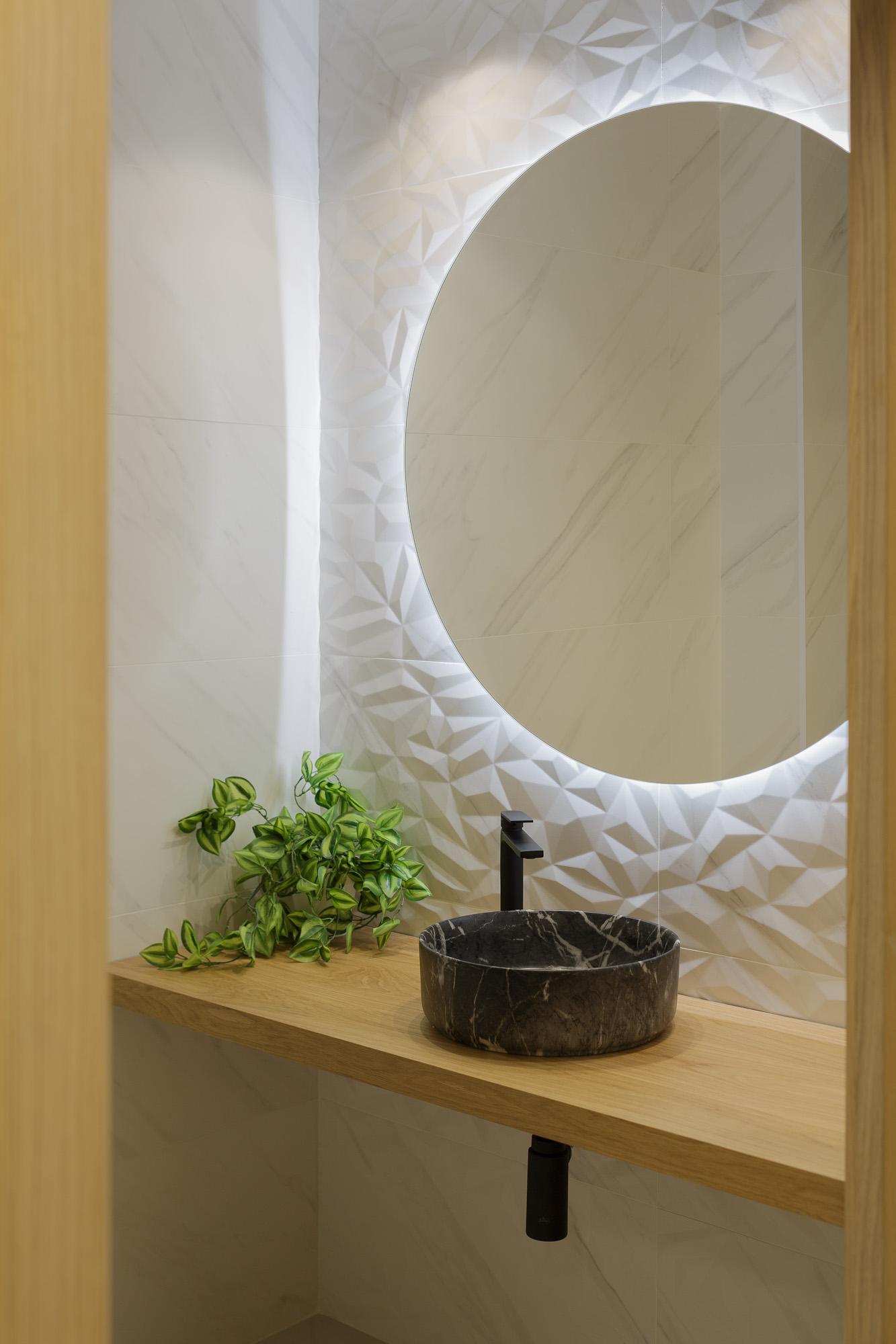 Detalle del baño con espejo circular retroiluminado con led